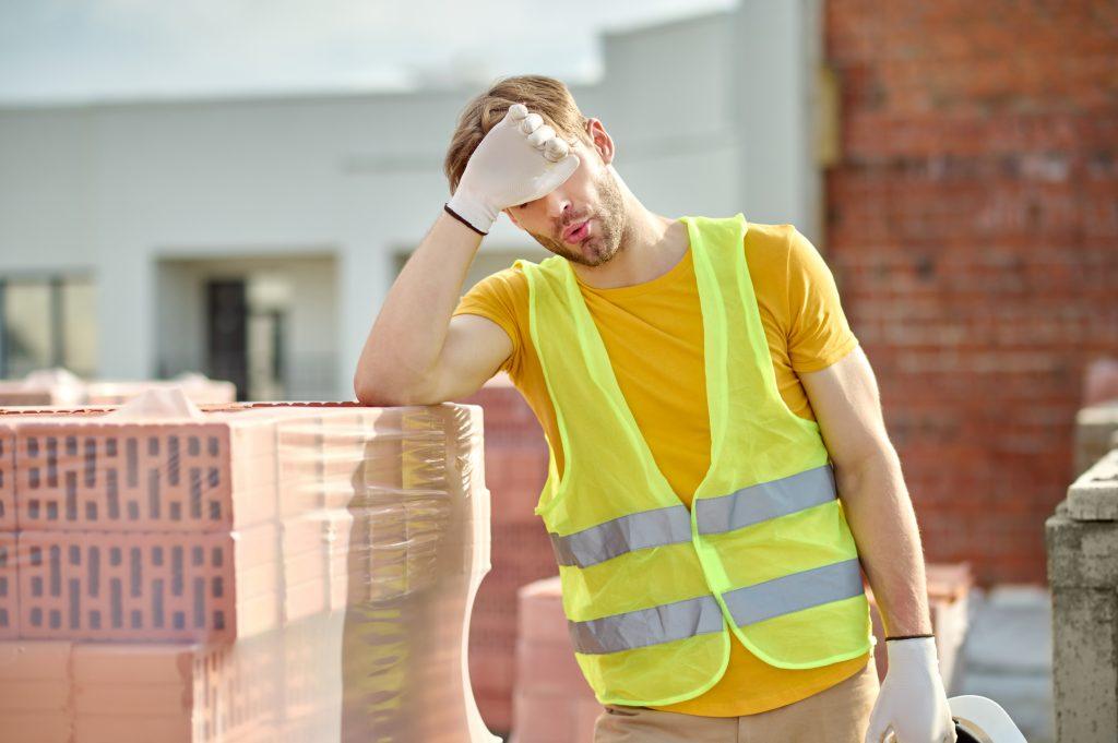 Tired worker touching face at construction site