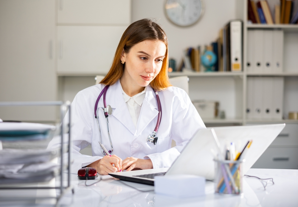 Young,Woman,Doctor,Assistant,Working,In,Medical,Office,Using,Laptop