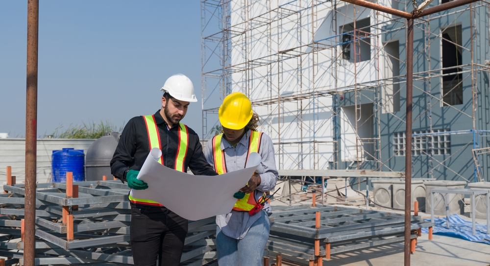 Two,Construction,Worker,Looking,At,A,Floor,Plan,,Standing,In